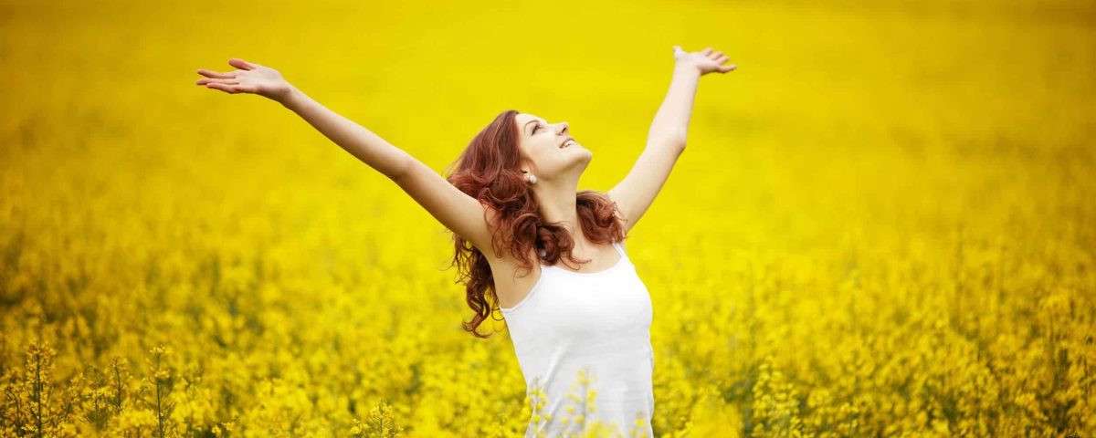 happy woman in a field of yellow flowers