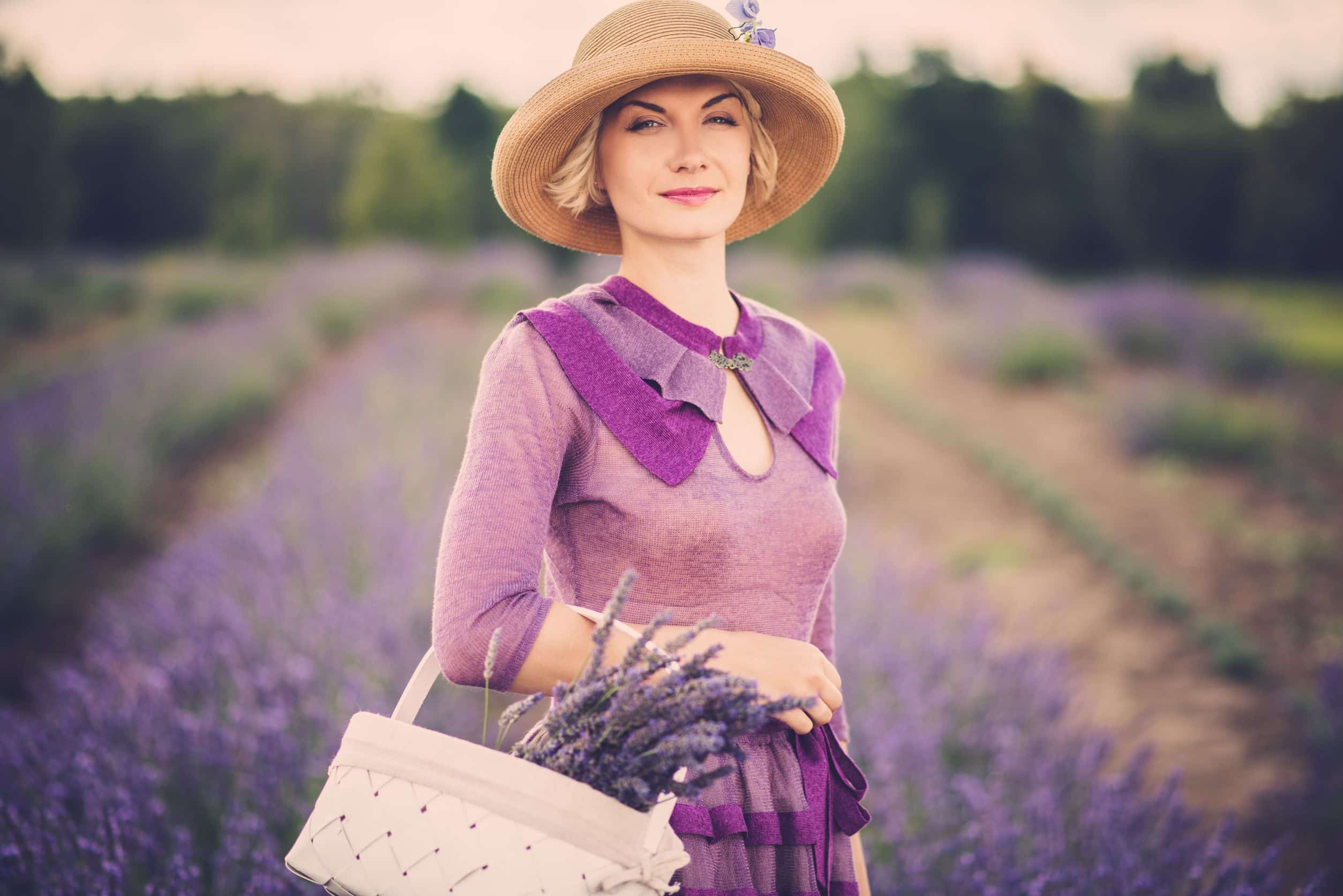 classy woman in a purple dress, standing in a field of lavender, with a basket of flowers