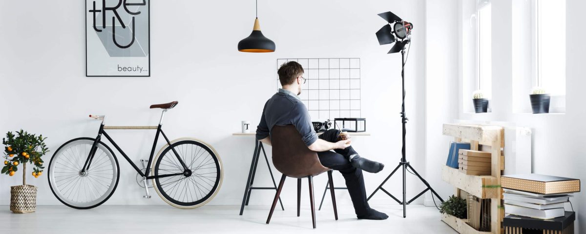 man sitting in an all-white room with minimalist furniture and black decor