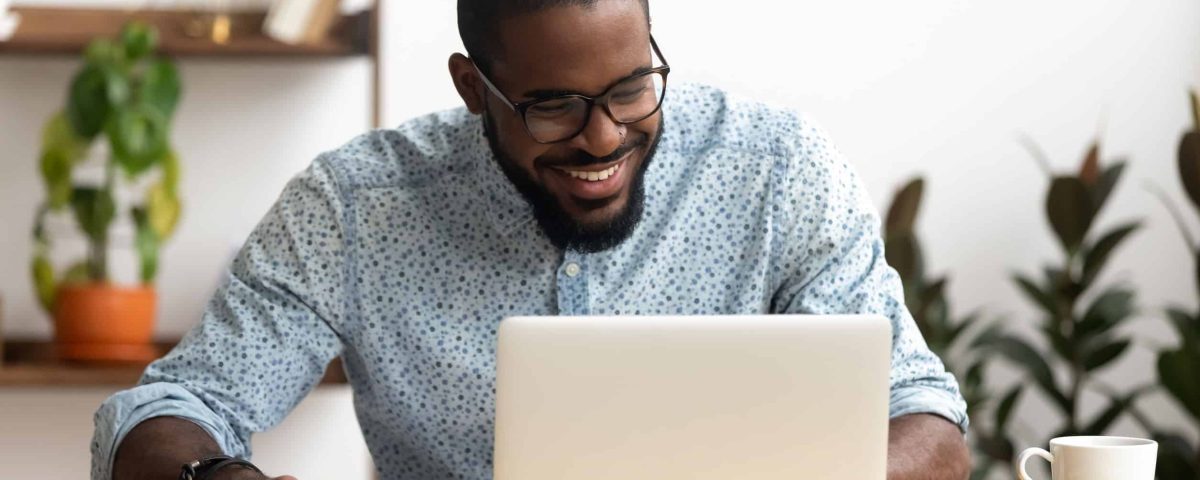 a smiling man on his laptop, planning social media for his small business