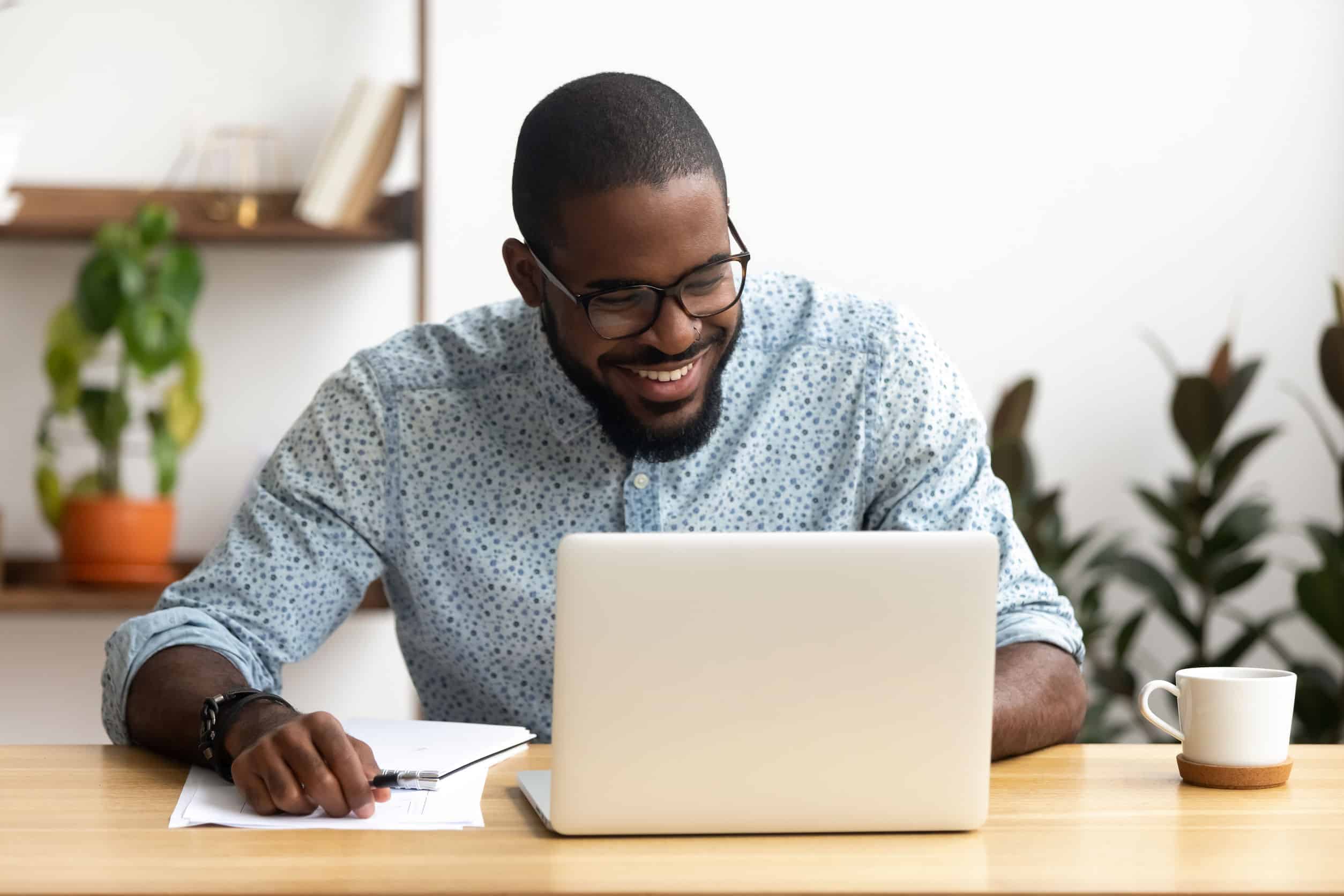 a smiling man on his laptop, planning social media for his small business