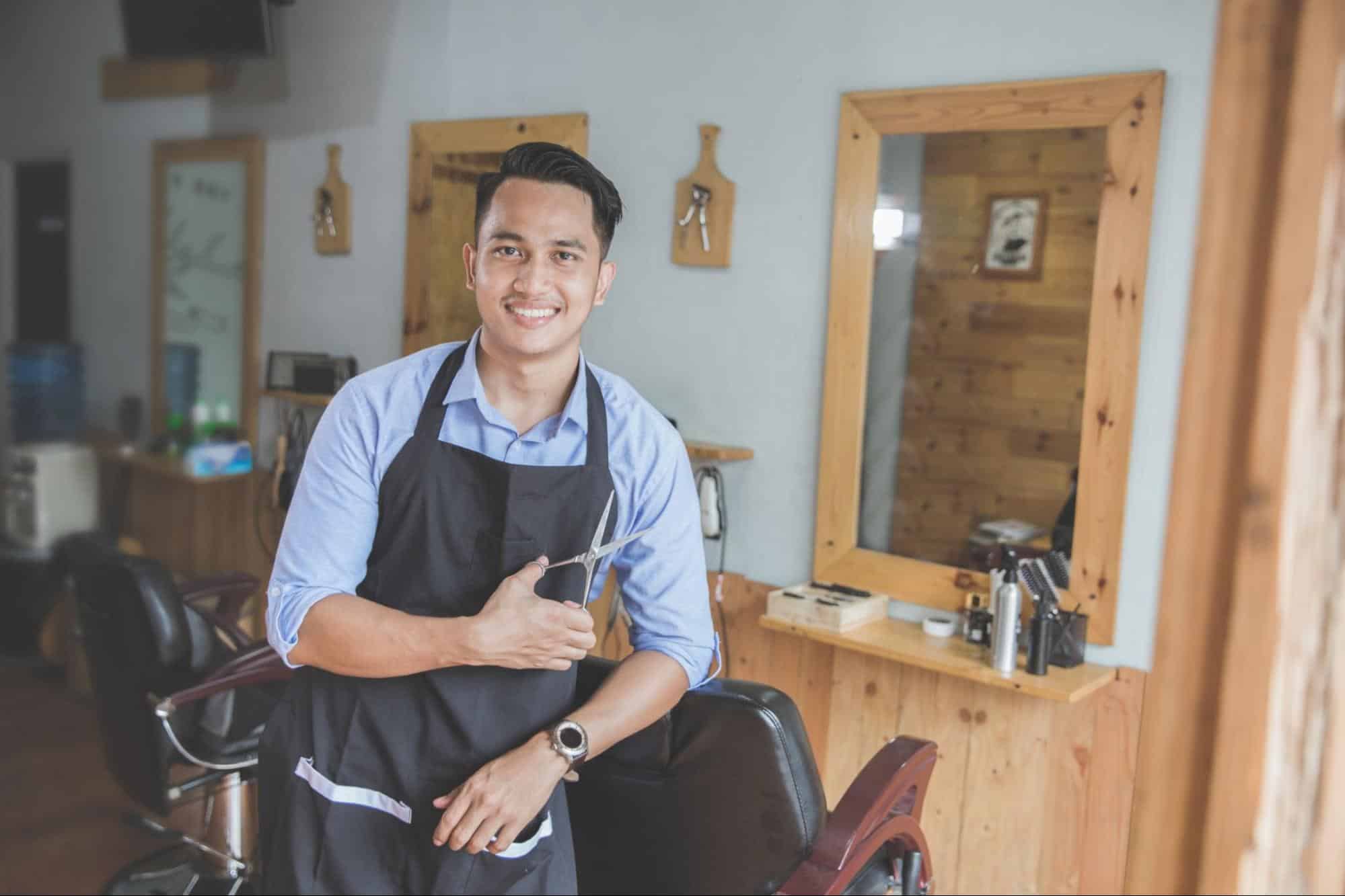 a barbershop owner in front of his chair and mirror