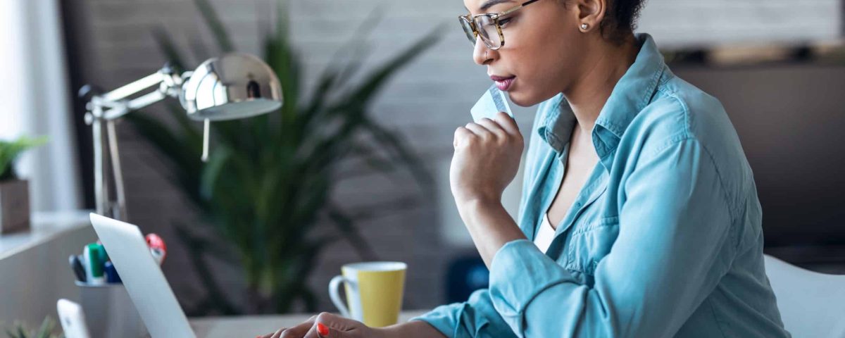 woman sitting alone and using her laptop to make an online purchase