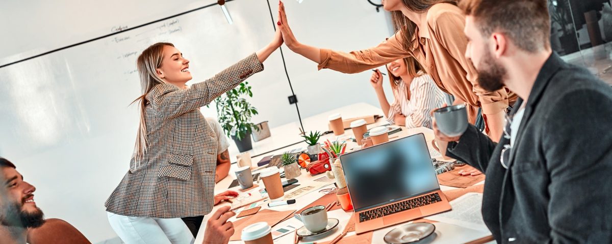 two marketing team members giving a high five over a conference table
